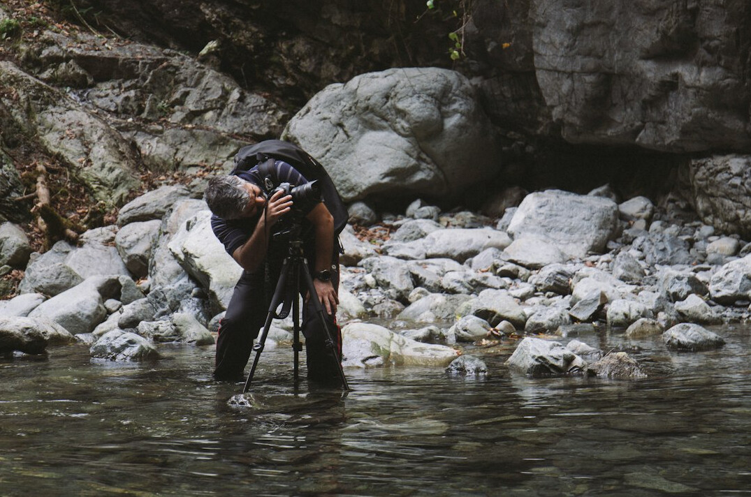 Journalist taking a water sample from a river for environmental testing